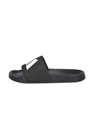 Sandalia tipo slide negra con una amplia tira superior con un logo blanco, suela plana y plantilla texturizada sobre un fondo blanco.