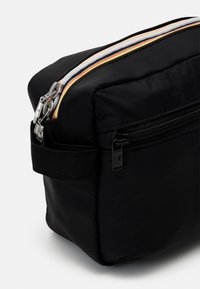 Black nylon cosmetic bag with a rectangular shape, dual zippers featuring orange and white accents, and an additional side zipper pocket.