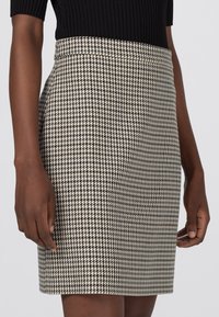 Mini sukně s kostkovaným vzorem v černé a krémové barvě, se střihovým přizpůsobením a hladkou strukturou, viditelným pasem a mírným pružením.