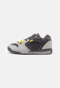 Black and grey sneaker with suede and leather materials, featuring yellow laces, perforated accents, and a low-top design.