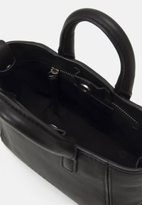Borsa a mano in pelle nera con manici corti, tasca interna con cerniera e finitura testurizzata. Presenta un interno foderato e un design elegante.