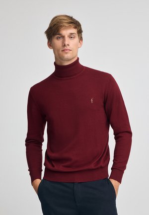 Maglione a collo alto borgogna in morbido tessuto a maglia, con colletto e polsini a costine, e un piccolo logo sul petto.