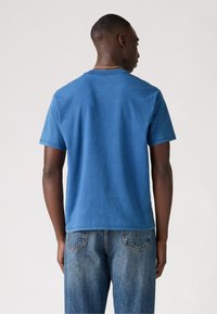 Blå bomull T-skjorte med rund hals og korte ermer, som viser en glatt tekstur, brukt sammen med lyseblå denimjeans.