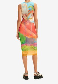 Ærmeløs, tætsiddende kjole med et farverigt, tropisk landskabsdesign. Fremstillet af letvægtsstof, med en knælang kant og slidse i ryggen.