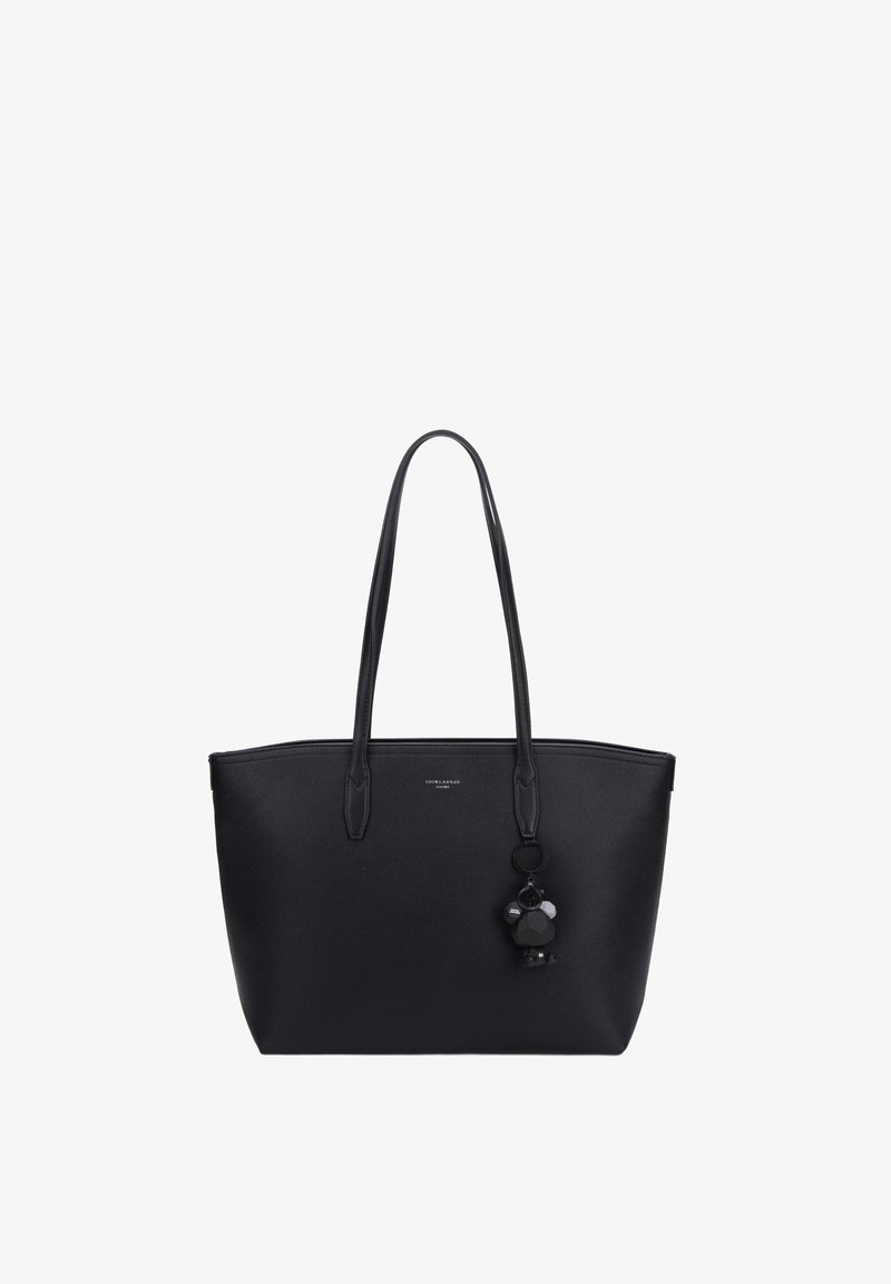 Sac fourre-tout en cuir noir avec de longues poignées et un petit charm en forme d'ours suspendu à une poignée, fond blanc uni.