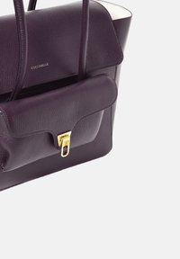 Sac à main en cuir violet au design structuré, avec poignée supérieure et une poche avant dotée d'un fermoir doré. Finition texturée.