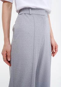 Grijze, lichtgewicht broeken met een elastische tailleband, voorzien van een soepele textuur, een getailleerde pasvorm en een voorplooi-detail.