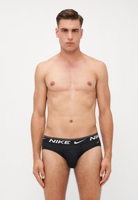 Schwarze Nike-Unterwäsche mit einem weißen Logo-Bund. Die Unterwäsche hat einen engen Sitz und eine glatte, weiche Textur.
