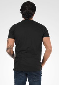 Sort kortærmet t-shirt i bomuld med en klassisk pasform, parret med blå denimjeans med baglommer og et struktureret design.