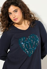 Langärmliges navy Top mit einem Herzdesign, das "PEACE LOVE" in Türkis zeigt, umgeben von floralen Mustern. Weicher Stoff, lässige Passform.