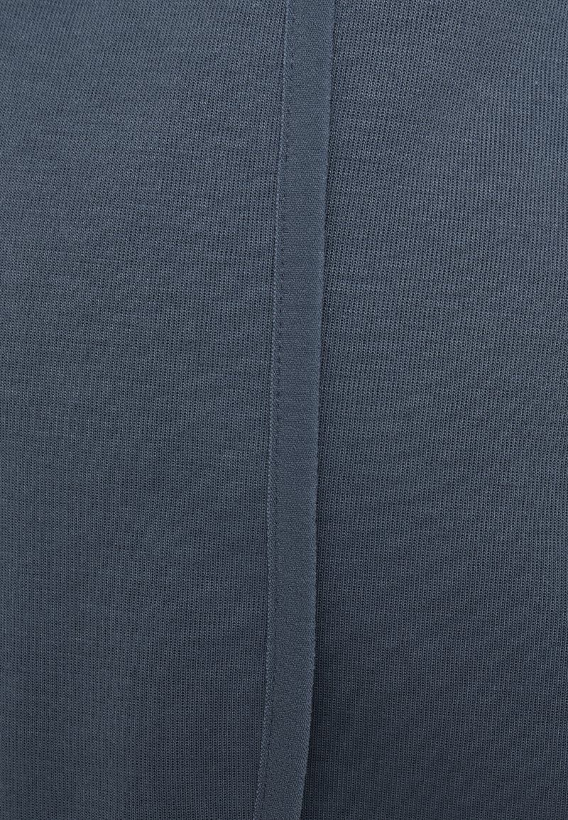 Tissu tricoté bleu marine avec une texture fine, présentant des coutures visibles le long des coutures et une surface lisse et uniforme.