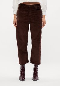 Bruine corduroy broek met een recht model, met een hoge taille, zakken en een zachte textuur. Gecombineerd met glanzende bordeauxrode enkellaarsjes.