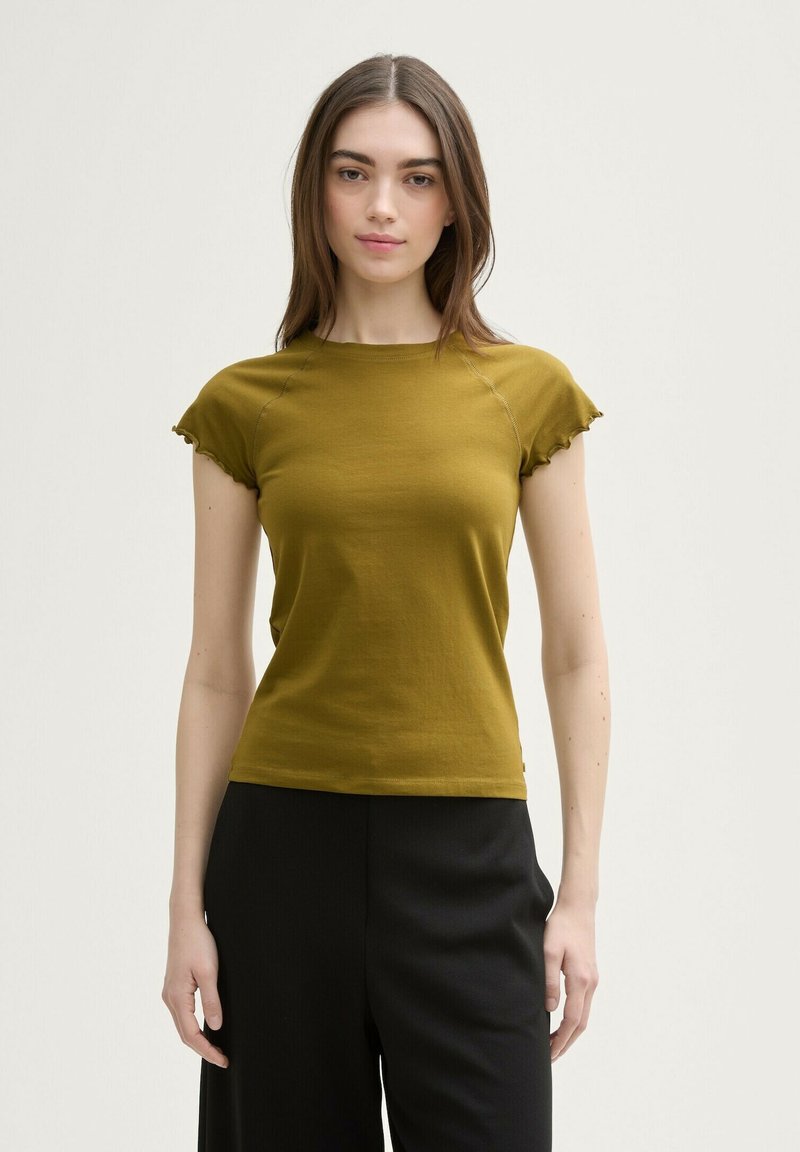 Top scurt de culoare verde măslinie, cu design ajustat, detalii cu cusături pe față și margini volan pe manșete; asortat cu pantaloni negri închiși.