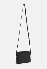 Black leather crossbody bag with a smooth texture, zip closure, and a long, adjustable strap. Compact rectangular design with simple accents.