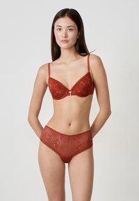 Sutién de encaje rojo y braguitas altas a juego, con patrones florales y bordes en forma de onda para un aspecto texturizado y una sensación ligera.