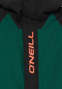 Grüne und schwarze Jacke mit einer schwarzen Frontklappe, auf der vertikal zentriert das leuchtend orangefarbene O'Neill-Logo abgebildet ist.
