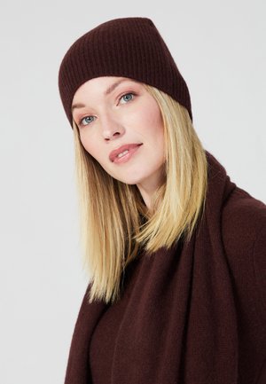 Berretto a maglia bordeaux con texture a coste, abbinato a una sciarpa coordinata. Materiale morbido, con un design aderente che si restringe alla sommità.