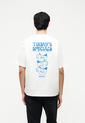 Άτομο με κοντά σκούρα μαλλιά φοράει λευκό μπλουζάκι που δείχνει στοιβαγμένες μπλε κούπες καφέ και κείμενο «ΣΗΜΕΡΙΝΕΣ ΠΡΟΣΦΟΡΕΣ» με ονόματα καφέ.