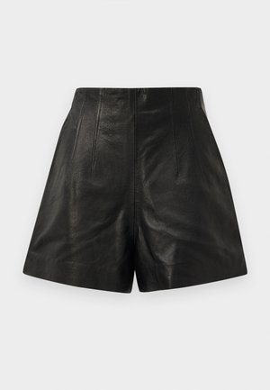 Aukštos juosmens juodos odinės šortai su vertikaliais siūlės detalėmis priekyje ir šiek tiek aptakiu kojų atidarymu ant vientiso fono.