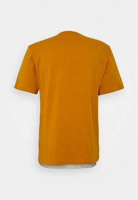 Kortärmad t-shirt i orange, tillverkad av mjuk bomull, med rundad hals och rak fåll. Bakdelen är enkel utan synlig logotyp.
