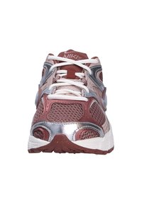 Běžecké boty Nike s burgundským síťovaným svrškem, stříbrnými akcenty a bílými tkaničkami. Mají texturovanou podrážku a zaoblený design špičky.
