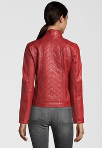 Rote Lederjacke mit hohem Kragen, gestepptem Rücken mit Zickzackmustern und schlanker Passform. Lange Ärmel und taillierte Silhouette.