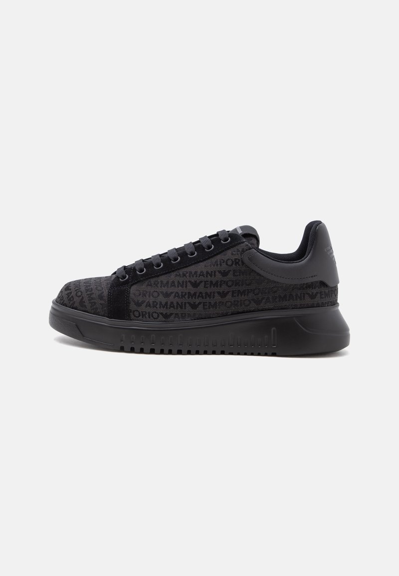 Baskets basses noires avec motif logo Emporio Armani embossé, lacets noirs et semelle épaisse, présentées en vue de profil du côté droit.