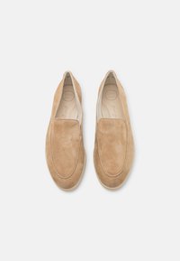 Ljusbruna mockaskor utan snörning med rundade tår, kontrasterande ljus sula och präglad "SUPER SOFT" märkning inuti skon.