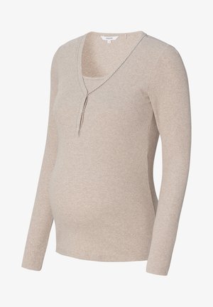 Langsleeve zwangerschapsblouse van zacht beige ribstof, met een V-hals en knoopaccenten. Aansluitende pasvorm voor een groeiende buik.