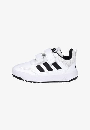 Zapatilla deportiva blanca con dos correas de velcro, diseño de tres rayas negras en el lateral y forro interior acolchado negro.