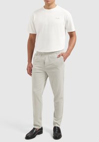 White cotton t-shirt with a round neckline. Light gray, lightweight trousers with an elastic waistband and side pockets. Black loafers.
