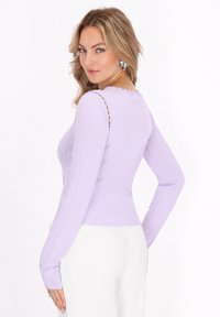 Top lungo a maniche lunghe di colore viola chiaro con righe texturizzate e scollatura a forma di scallop, dotato di dettagli con spalle scoperte e design aderente.