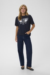 Jūrinis marškinėliai su baltu grafiniu spaudiniu, laisvas kirpimas; derinami su tamsiai mėlynomis tiesiomis kelnėmis; juodos ir baltos taškuotos balerinos.