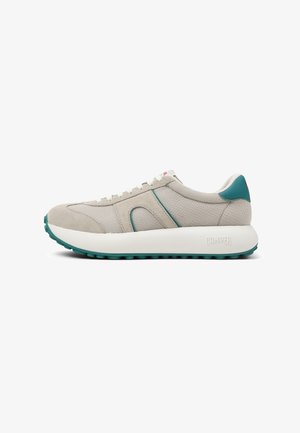 Beige lenkkari, jossa on verkko- ja mokkaelementtejä, teal-värisiä yksityiskohtia, valkea pohja, pyöreä kärki ja kumipohja, jossa on pito-kuvio. Brändin nimi kantapäässä.
