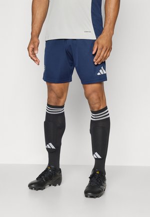 Men's sports clothing featuring a light gray shirt, navy blue shorts, black socks with white stripes, and black soccer cleats with yellow accents.