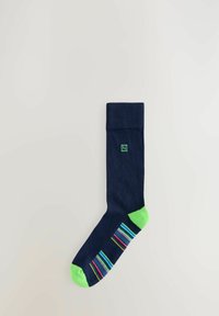 Calcetines de color marino con puño y punta verdes, con rayas multicolores en el lateral. Hechos de una tela texturizada.