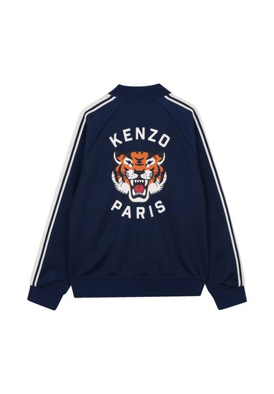 Veste bleu marine avec des rayures blanches sur les manches, arborant une grande tête de tigre orange féroce et le texte "KENZO PARIS" dans le dos.