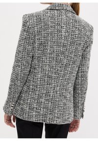 Černo-bílý tvídový blazer s texturovaným kostkovaným vzorem, klopovým límcem a čtyřmi knoflíkovými detaily na rukávech, přiléhavý střih.