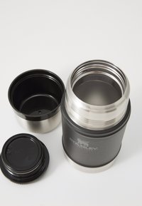 Stainless steel vacuum thermos with a matte black exterior. Features a removable black lid and internal cup. Engraved Stanley logo.
