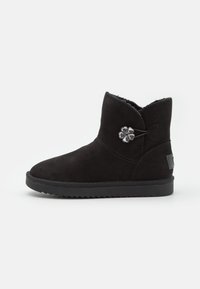 Stivaletto alla caviglia in suede nero con fodera in pelliccia sintetica, punta arrotondata, dettagli cuciti e decorazione floreale sul lato. Suola in gomma.