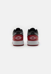 Sneaker basse rosse e nere con tomaia in pelle, suola intermedia bianca e logo ricamato sul tallone. Presenta un collare imbottito e una suola testurizzata.