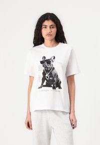 White cotton t-shirt features a graphic of a French Bulldog wearing sunglasses, with text and design elements printed around it.