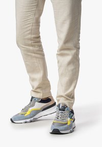 Sportliche Sneaker in einer Farbkombination aus Grau, Gelb und Blau, gefertigt aus einer Mischung aus Wildleder und Mesh-Materialien; dicke weiße Sohle mit Profilmuster.