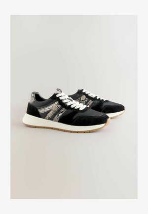Černé sportovní boty s akcenty z semiše a hadího vzoru, bílé šňůrky a lehká gumová podrážka. Vyznačují se kontrastními materiály a texturami.