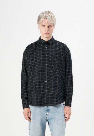 Black shirt with white grid pattern, button-down collar, long sleeves, and chest pocket. Fabric appears smooth with a structured fit.