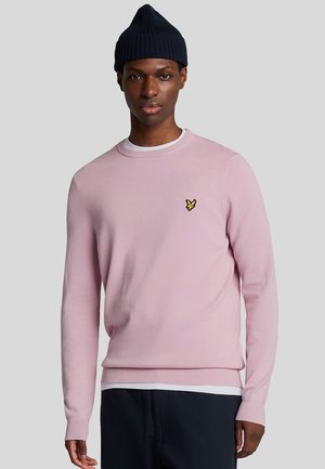 Pull en maille rose pâle avec un col rond et des poignets côtelés, arborant un petit logo de papillon jaune sur la poitrine gauche.