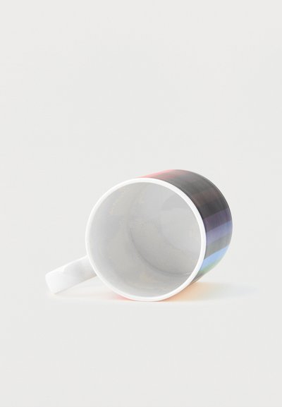 Tasse en céramique blanche avec des rayures horizontales arc-en-ciel, posée sur le côté sur un fond blanc uni.