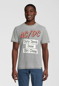 Grå bomullst-shirt med en djärv svart och röd AC/DC-logotyp och texten: "Dirty Deeds Done Dirt Cheap." Vanlig passform, kort ärm, rund hals.