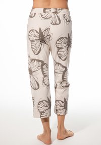 Cremefarbene Caprihosen aus Stoff mit Schmetterlingsdruck in Dunkelbraun. Elastischer Bund, verkürzte Länge und glatte Textur.