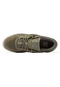Olivgrön sneaker med ovandel i mocka och nät, perforerade detaljer, platta snören, vadderad krage och logopatch på tungan. Vit gummisula.